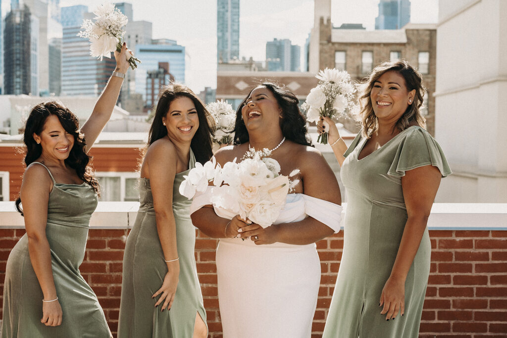 Bridal party laughing together on a rooftop in Brooklyn for their wedding party photos.
