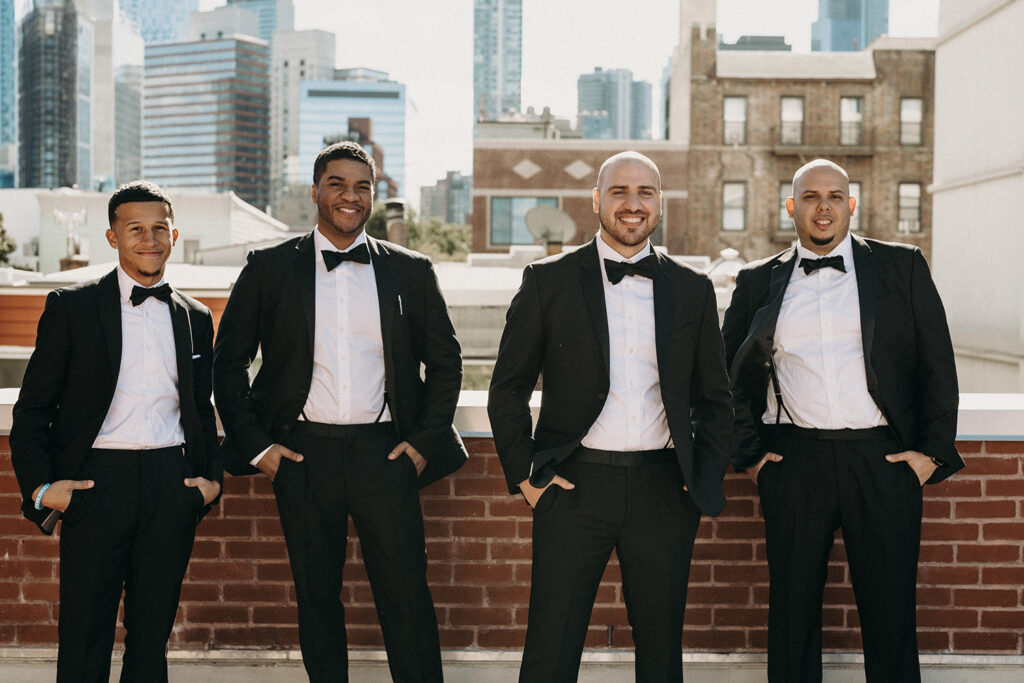 Groom and his groomsmen group photo on a rooftop in Brooklyn during their wedding party photos.