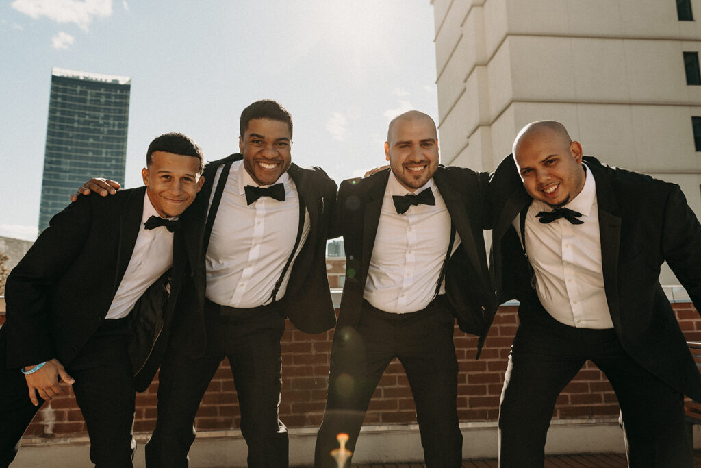 Groom and his groomsmen huddling together to get hype during wedding party photos.