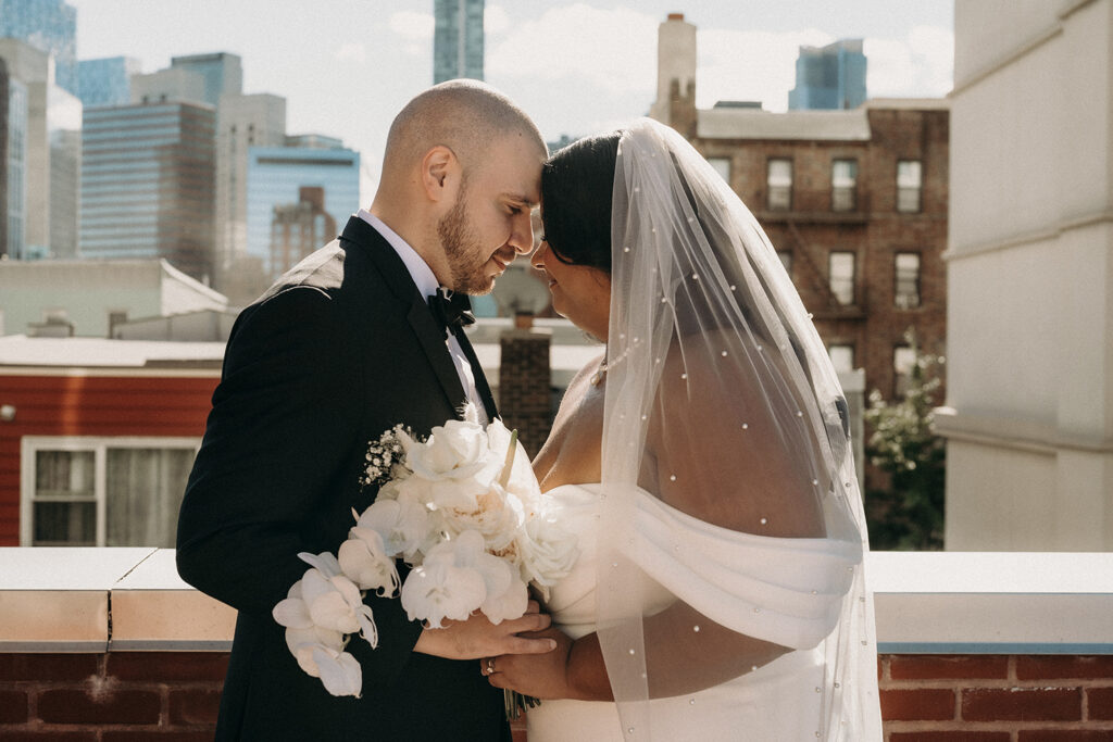 Photo of a bride and groom forehead to forehead on a rooftop in Brooklyn, NY