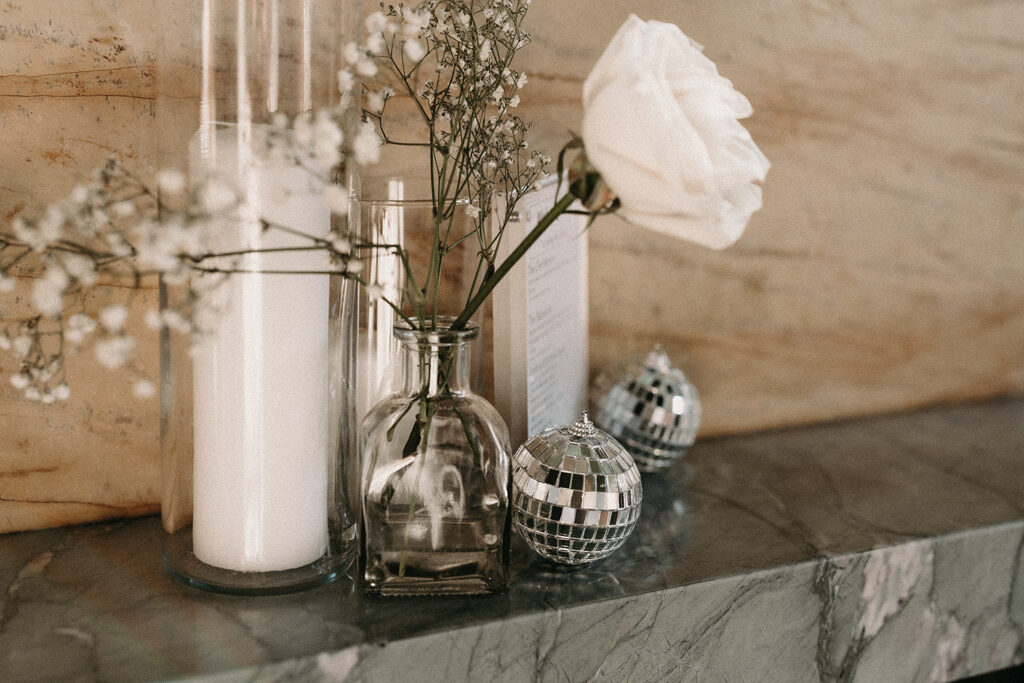 Disco balls, white roses and baby's breath wedding venue details.