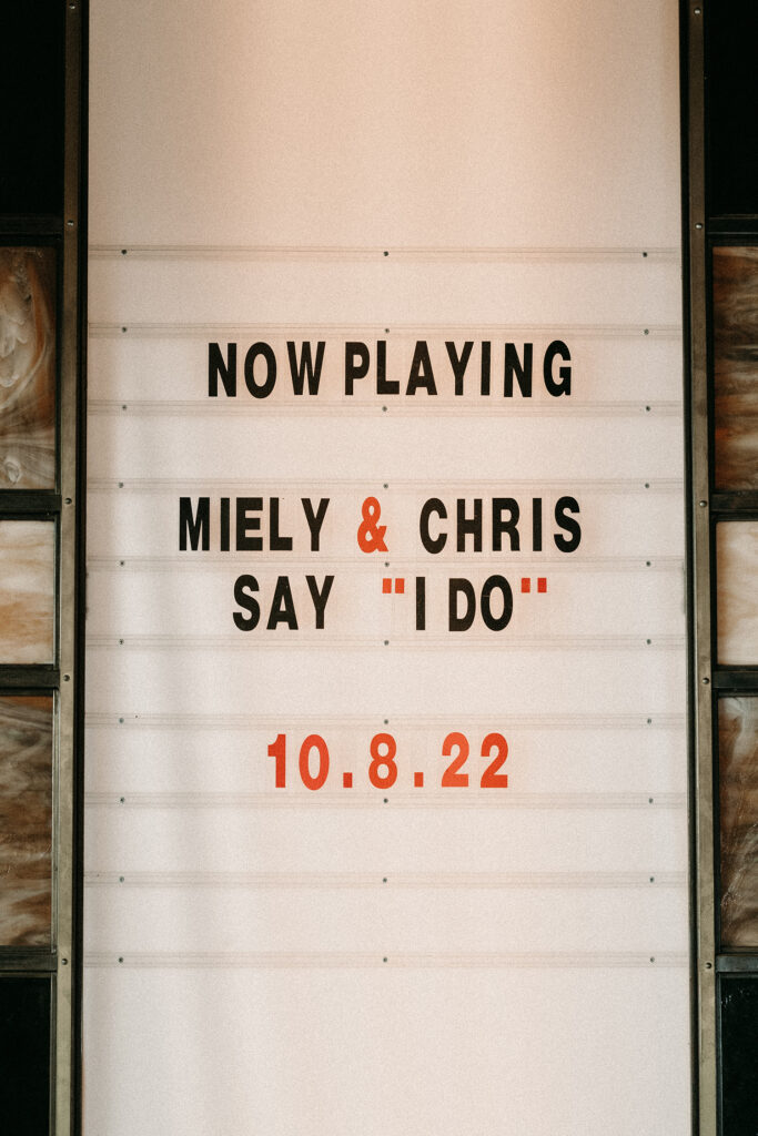 Now playing sign for a bride and groom's movie theatre wedding day.