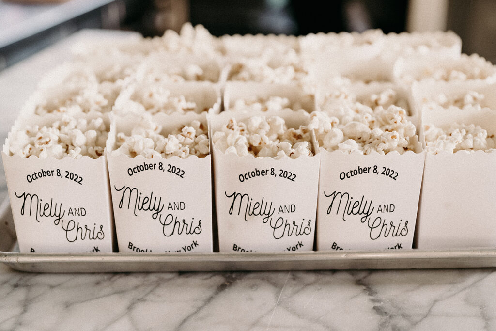 Popcorn snacks in personalized containers set out to greet guests at a movie theatre wedding in Brooklyn, NY.