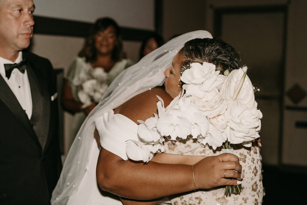 Bride hugging her mother after walking into their movie theatre ceremony.