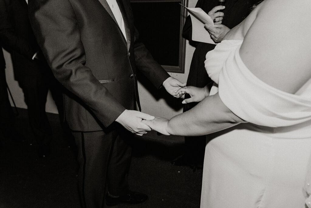 Bride and groom holding hands during their ceremony in a movie theatre.