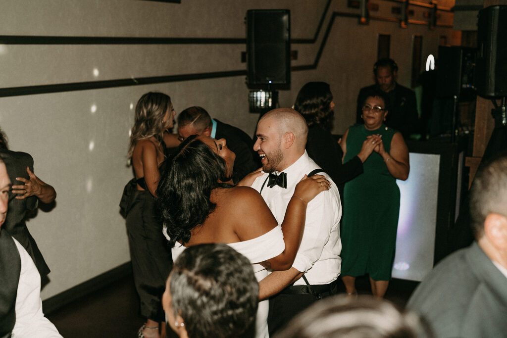 Bride and groom sharing a sweet moment of laughter on the dance floor during the reception.