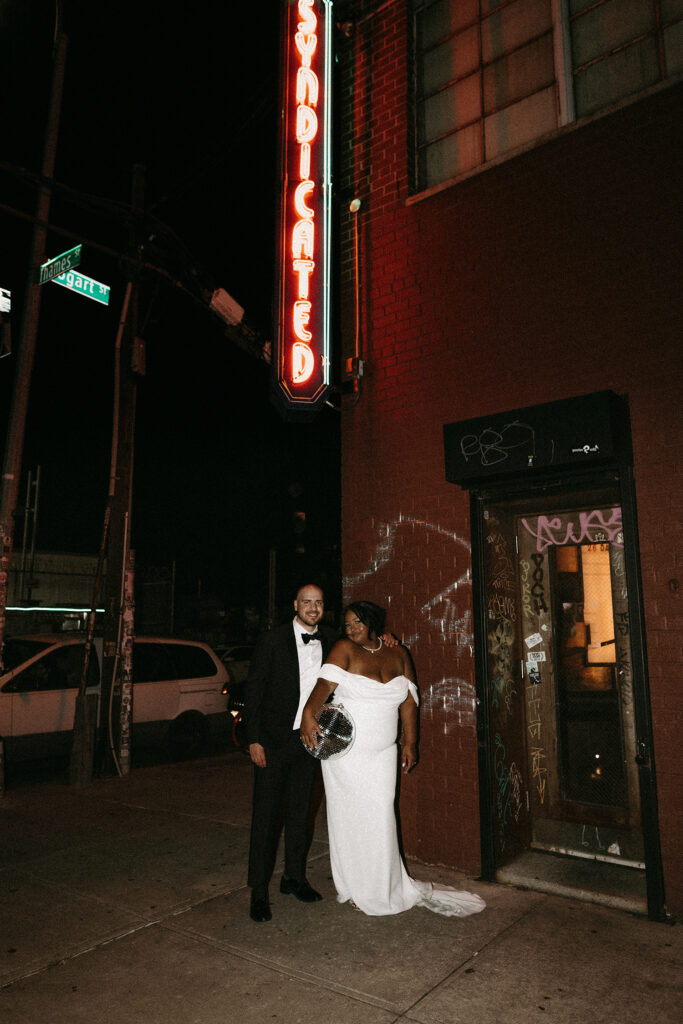 Direct flash photo of a bride and groom with the neon movie theatre sign at Syndicated in Bushwick Brooklyn, NY.