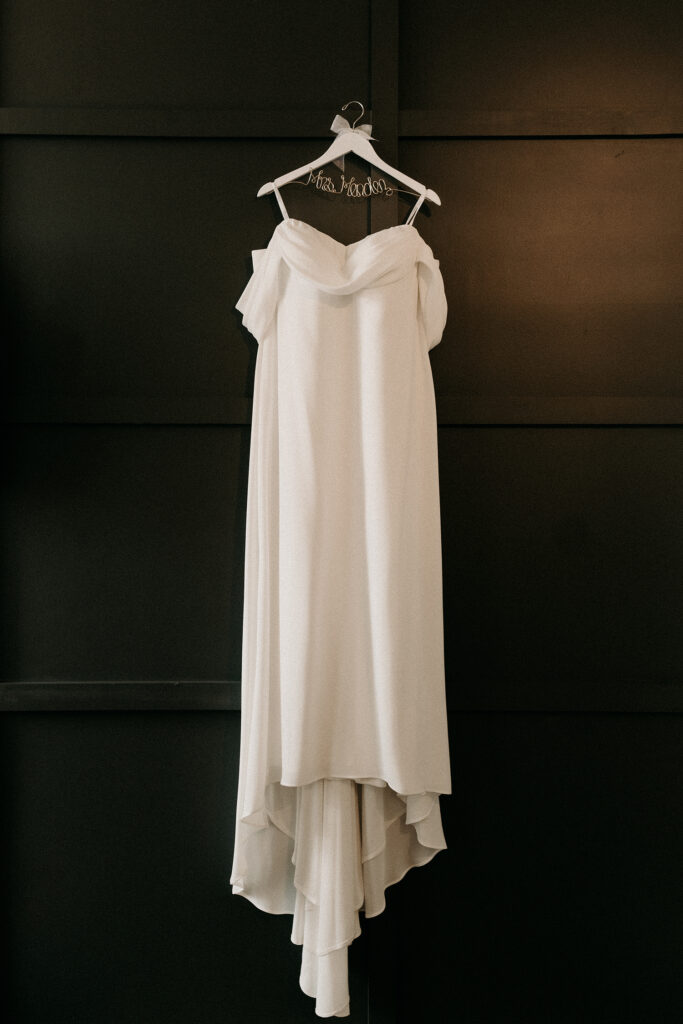 Simple and elegant wedding dress hanging on a customized hanger.