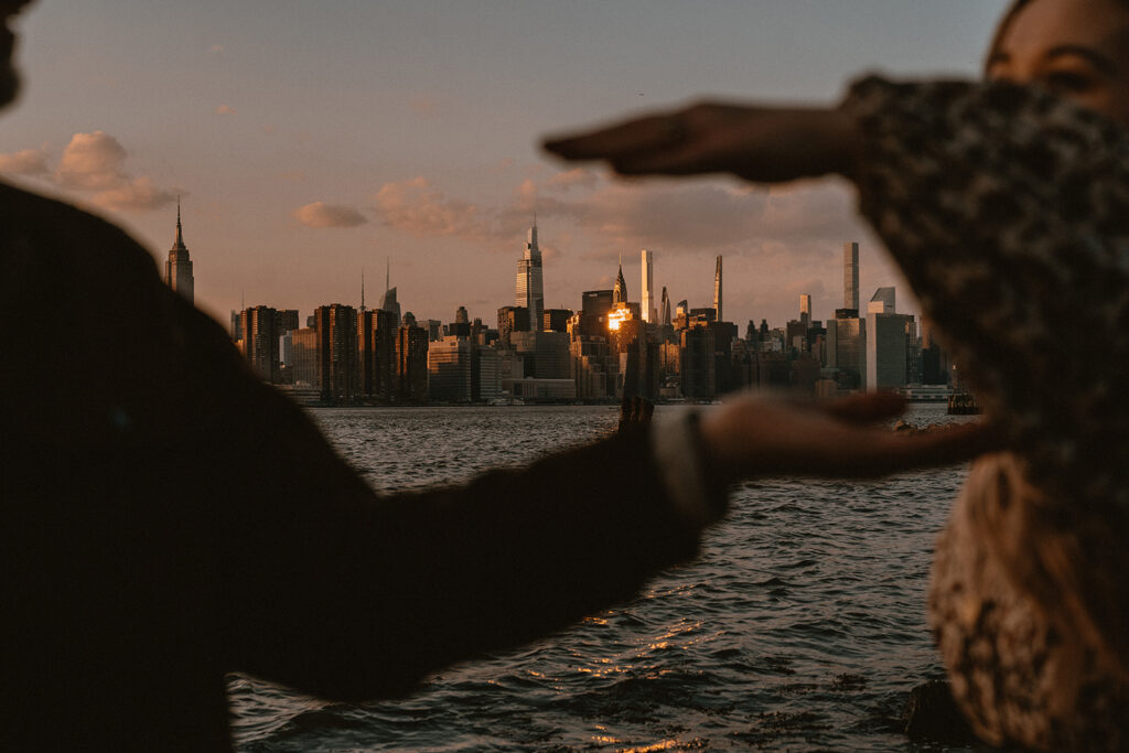 NYC skyline between a couple's hands during blue hour.