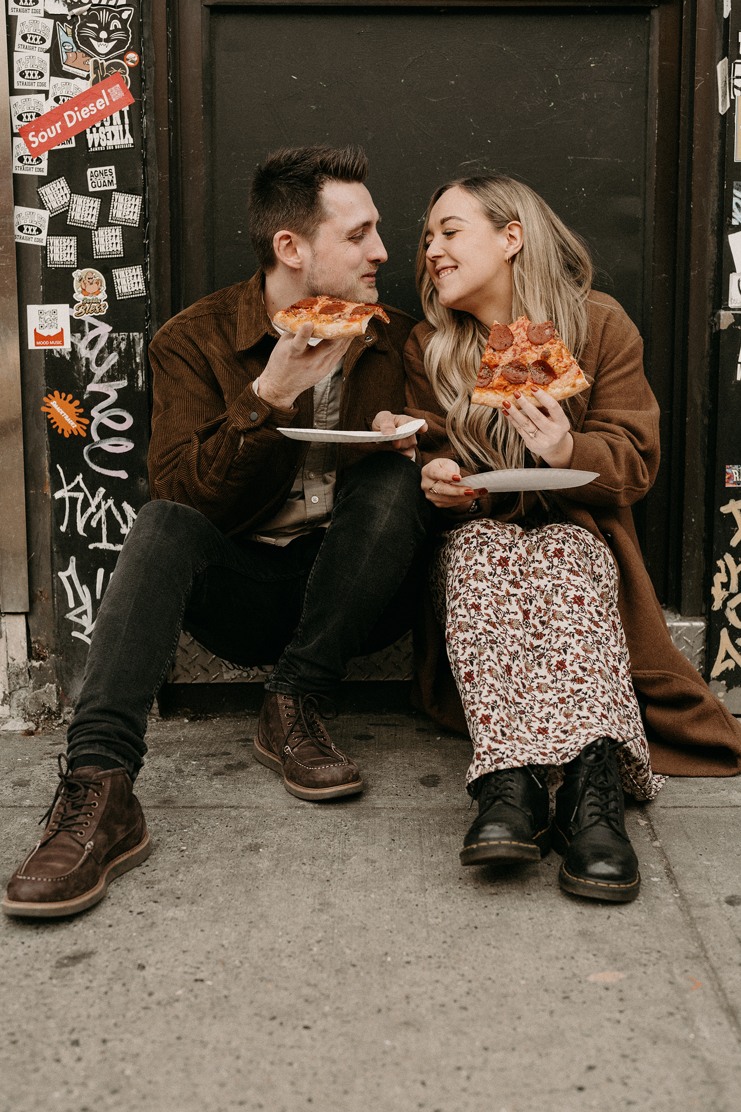 Cozy cuddles on a NYC stoop while eating pizza during engagement photos in Williamsburg.