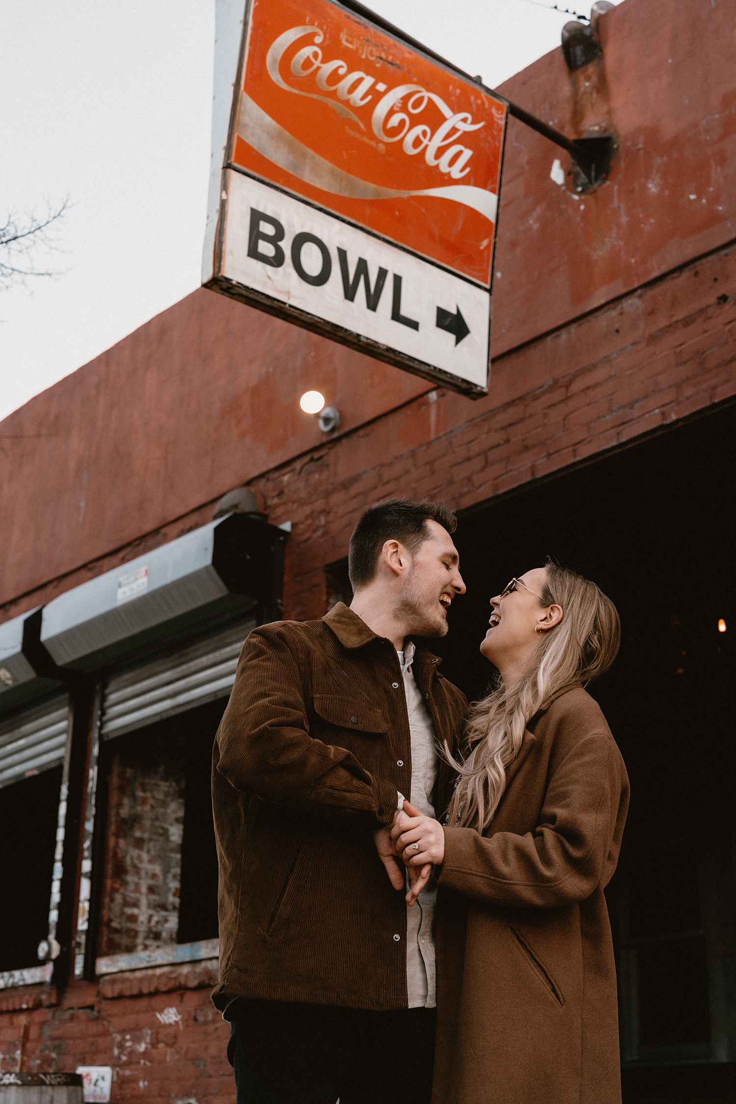 Couple laughing together on the streets of Williamsburg during their engagement session.