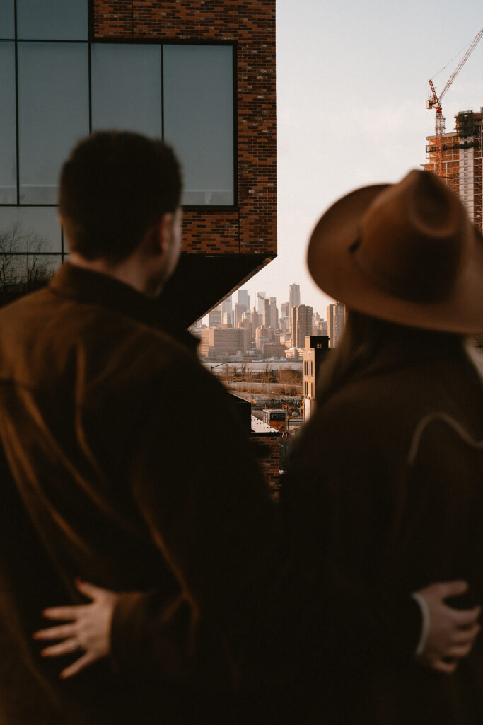 Couple overlooking the NYC skyline from a rooftop during their engagement photoshoot in Williamsburg.