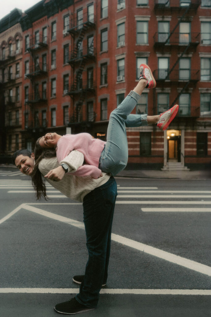 A man playfully lifts his wife on his back on the charming streets of West Village.
