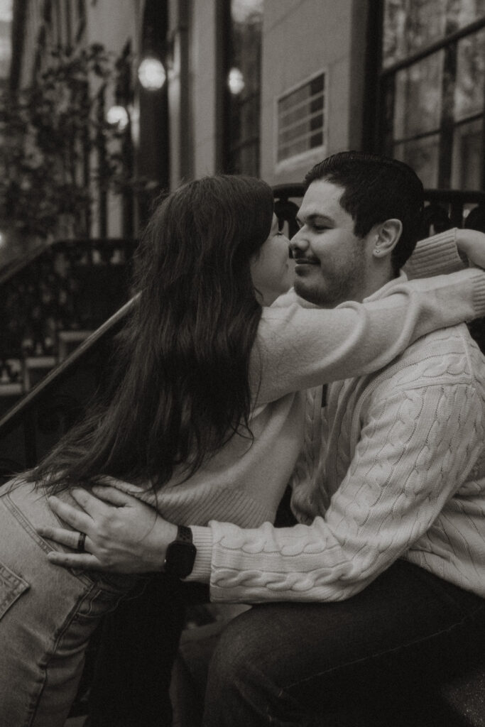 While sitting on a moody brownstone stoop, a couple shares a little snuggle.