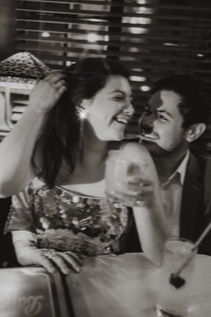 A candid moment of laughter between a couple in a retro cocktail bar in Manhattan.