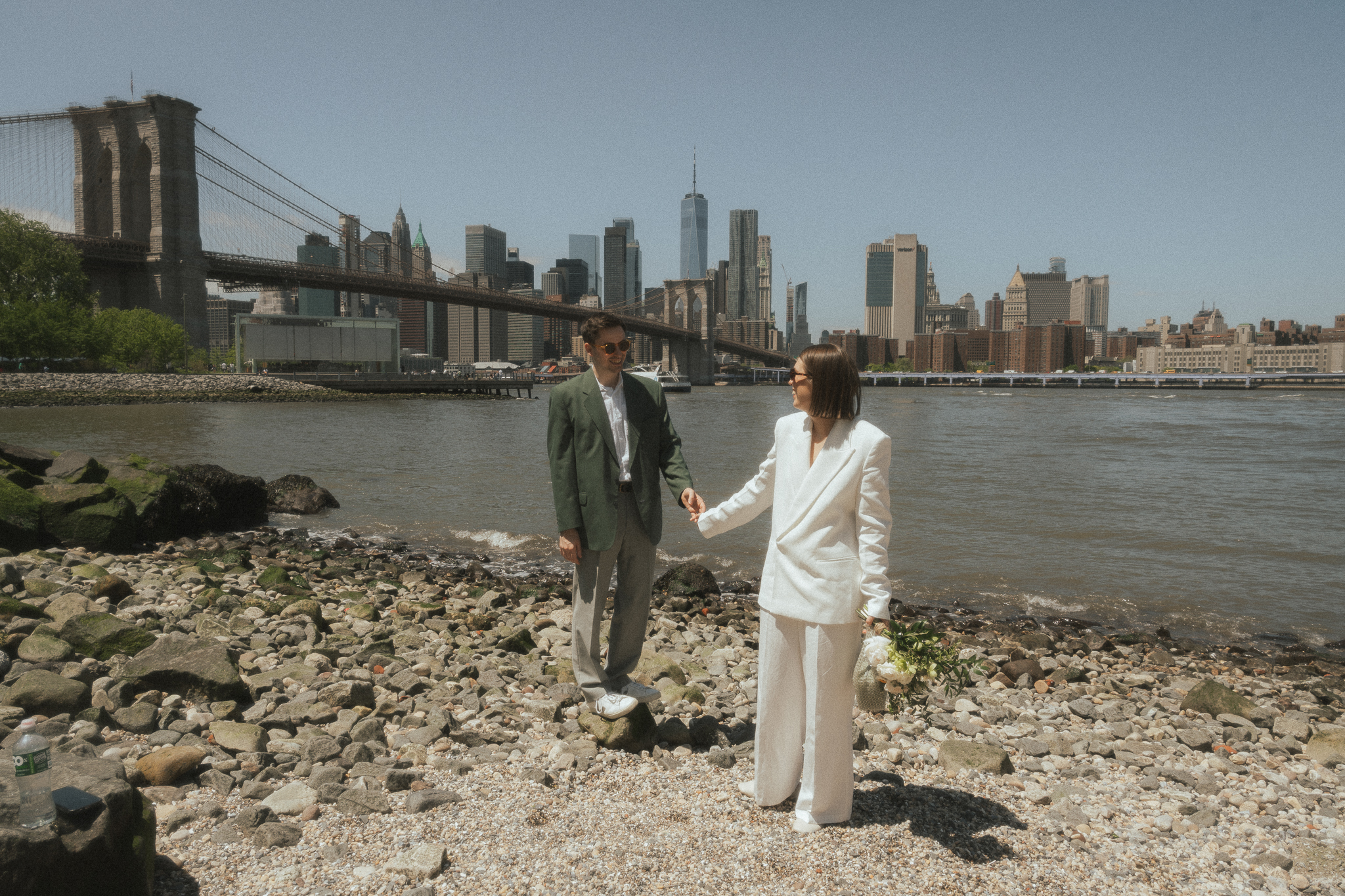 Amongst the rocks of Pebble Beach in Brooklyn, Melissa leads Will along the water during their NYC elopement.