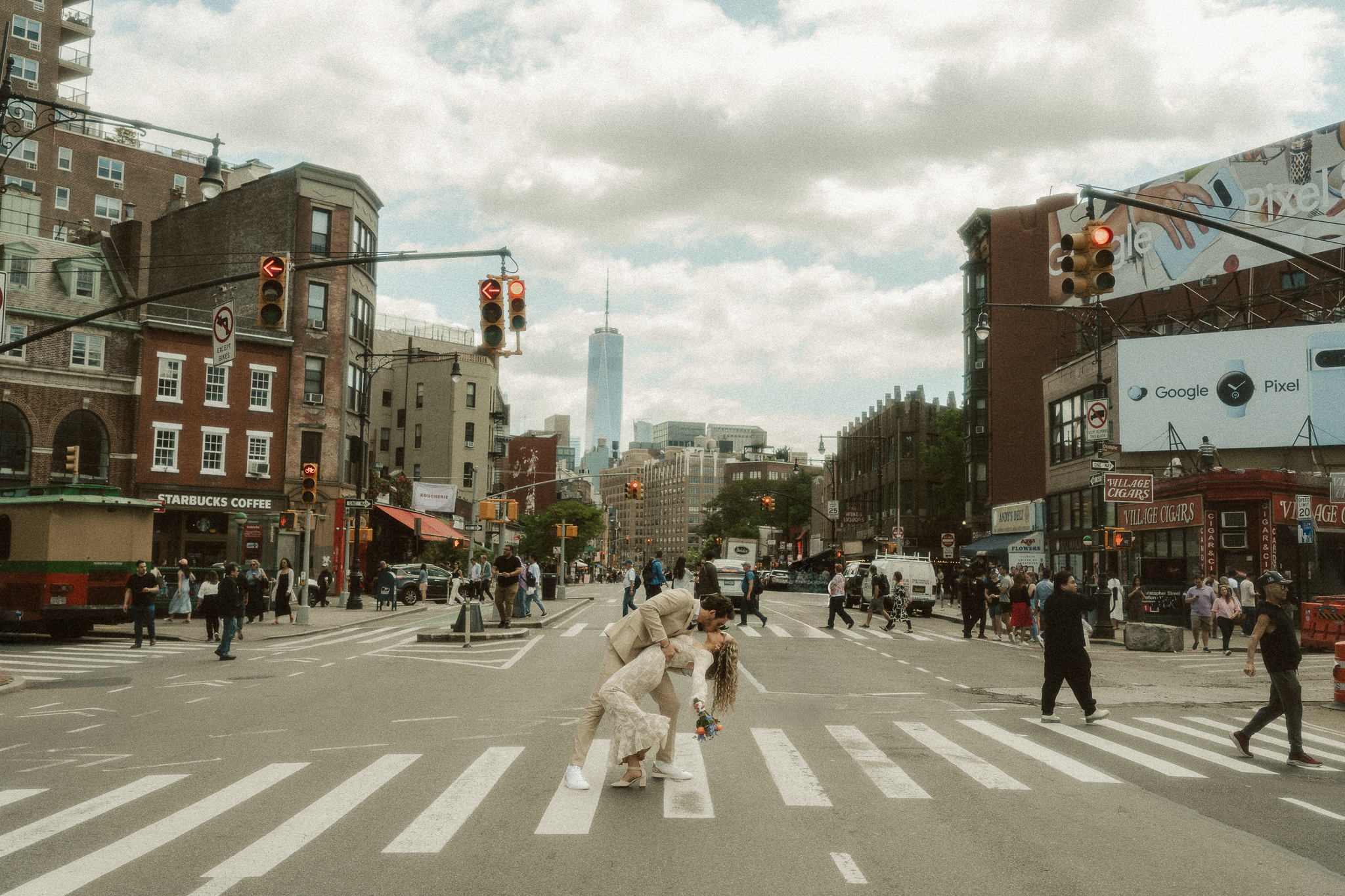 An iconic dip kiss between a bride and groom in a crosswalk in west village with the manhattan skyline in the background.