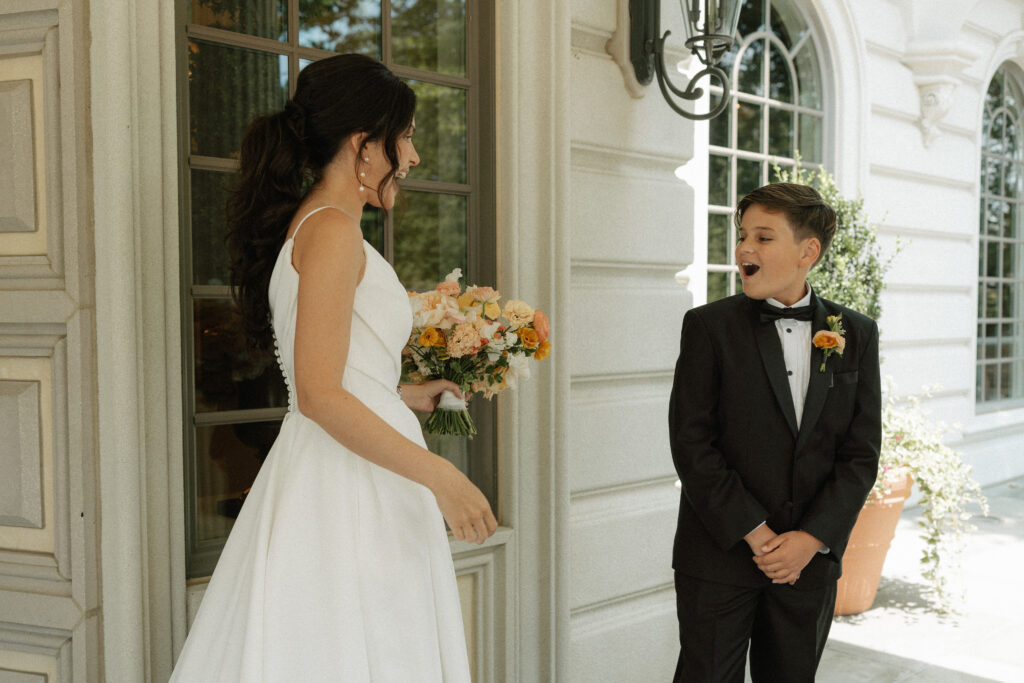 A bride's son gasps excitedly after seeing his mom for the first time on her wedding day during their first look.