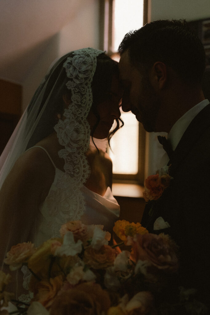 A warm silhouette of a bride and groom in a catholic cathedral after their ceremony.