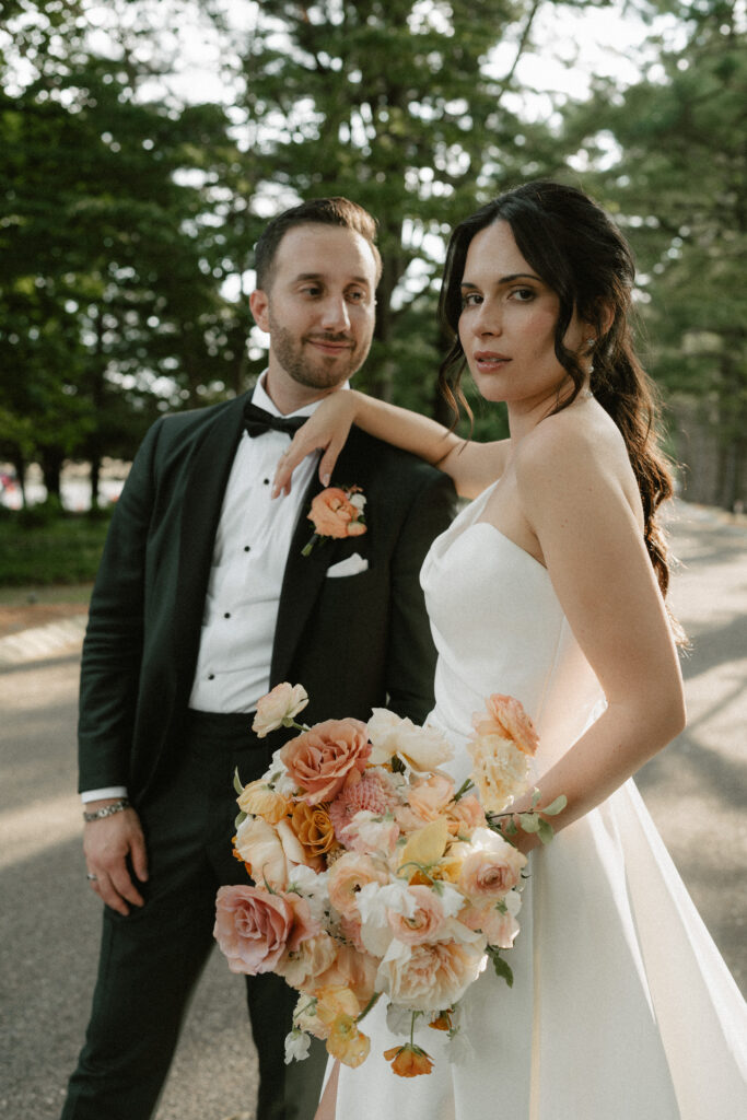 A bride leans on the shoulder of her groom and looks over her shoulder.