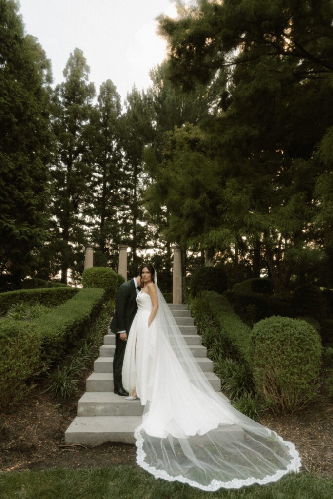 Bride and groom standing on the steps inside a luxurious garden at the Ashford Estate.