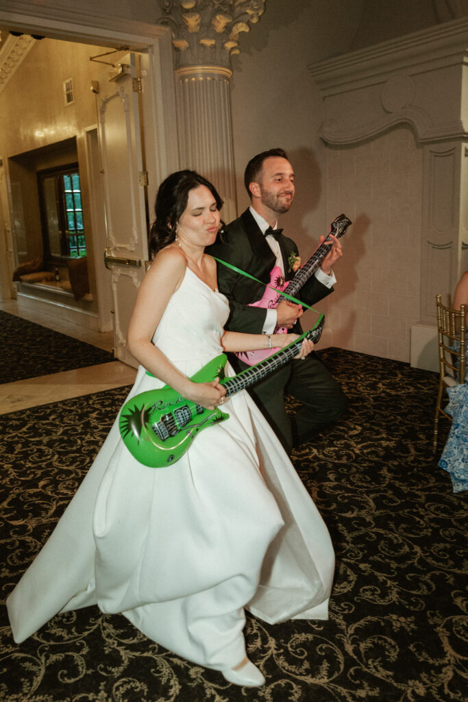 Showing off their playful personalities, a couple enters their reception with inflatable guitars pretending to play!