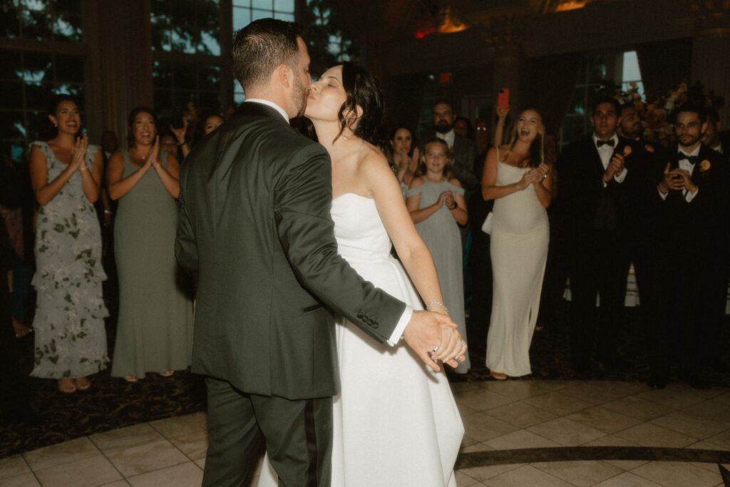 During their first dance, a bride and groom share a kiss.