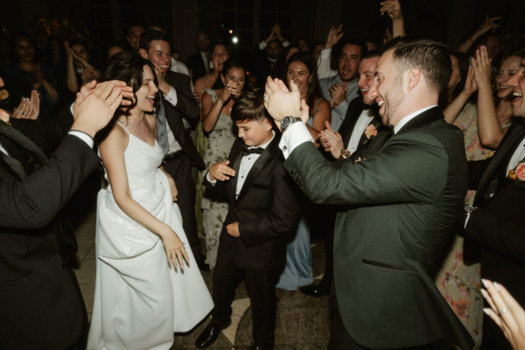 A bride and groom dance with their son in the middle of the dance floor at their wedding reception.