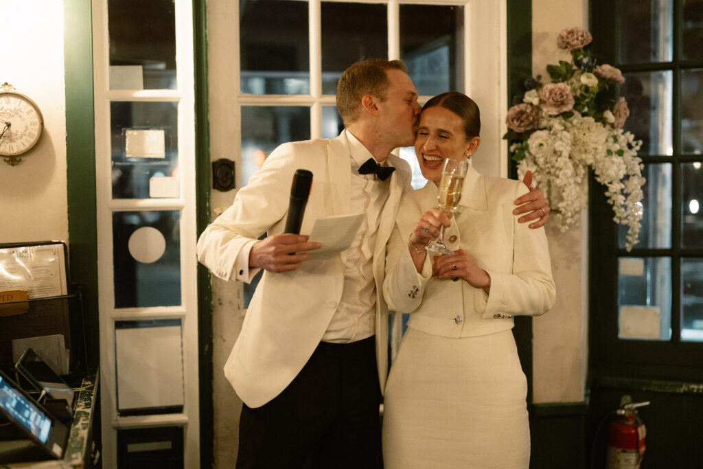 Quick PDA with bride while groom gives  speech to guests 