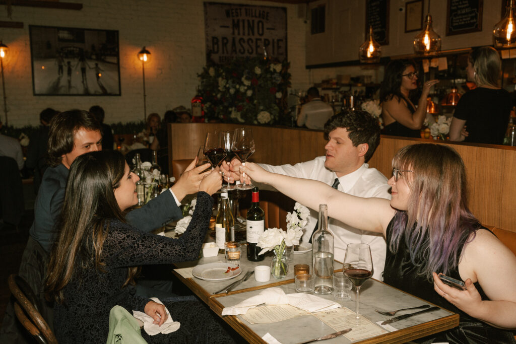 Guests hold up their glasses to toast bride and groom at Mino’s Brasserie