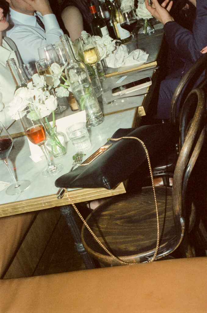 detail film shot of black handbag on corner of dinner table during wedding reception 