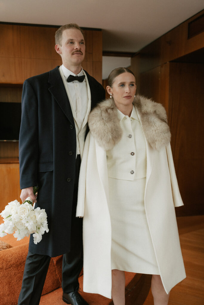 Winter elopement outer wear with groom in Navy Pea Coat and Bride in a off white trench with faux fur  color