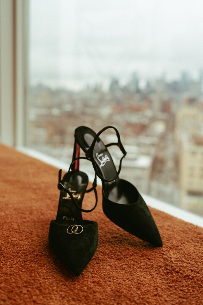 Detail Image Louboutin black heels sitting in window with NY cityscape background.