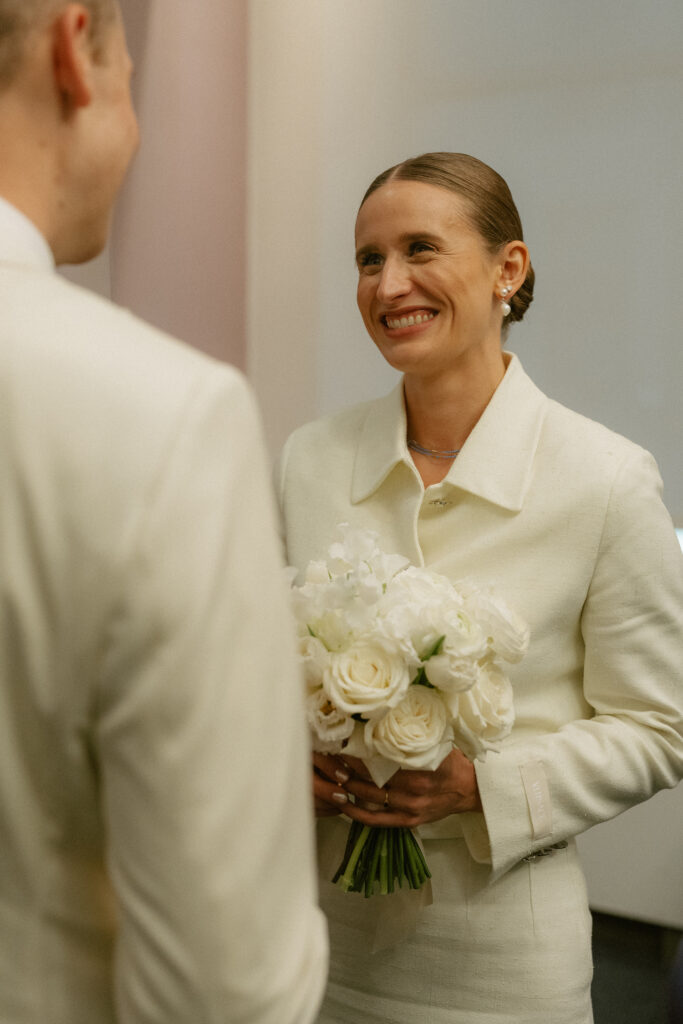 short stem white roses bouquet in front of bride in off white alternative wedding dress suit