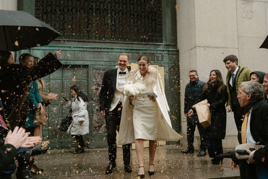 bride and groom exit under shower of dried flowers thrown by closest friends and family for their hybrid wedding elopement