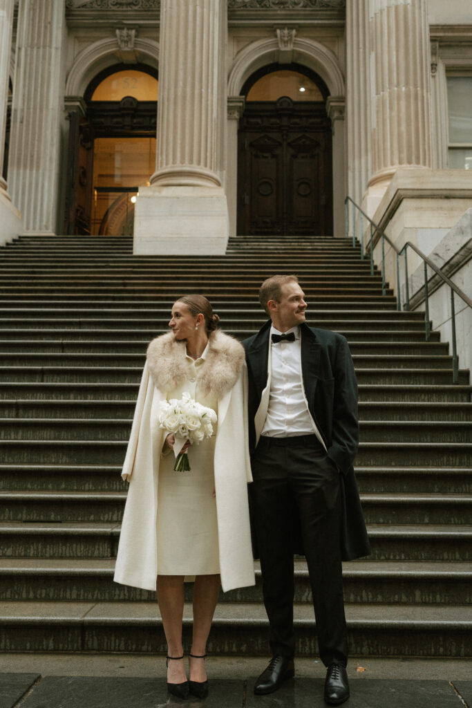 formally dressed standing side by side on city hall steps with columns in background