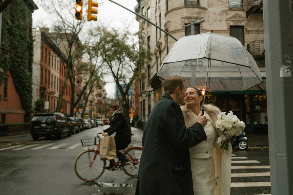 Vintage bike in background of married couple on sidewalk under clear umbrella