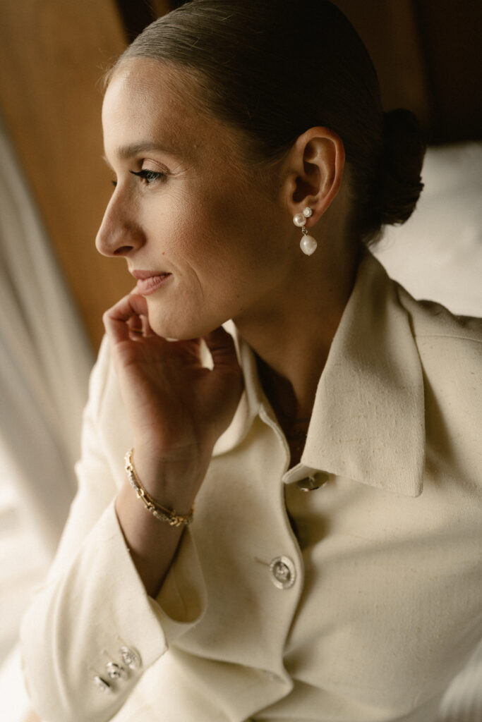 close-up-profile-view-of bride-looking-out-window-with-natural-day-light-on-makeup.