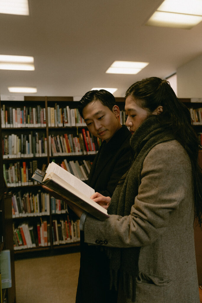 Warm and cozy engagement photos in a library for a winter photoshoot.