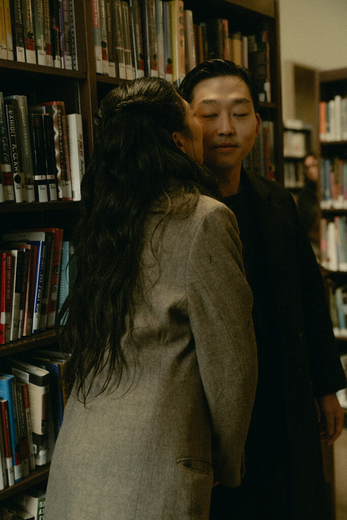 Warm and cozy engagement photos in a library for a winter photoshoot.